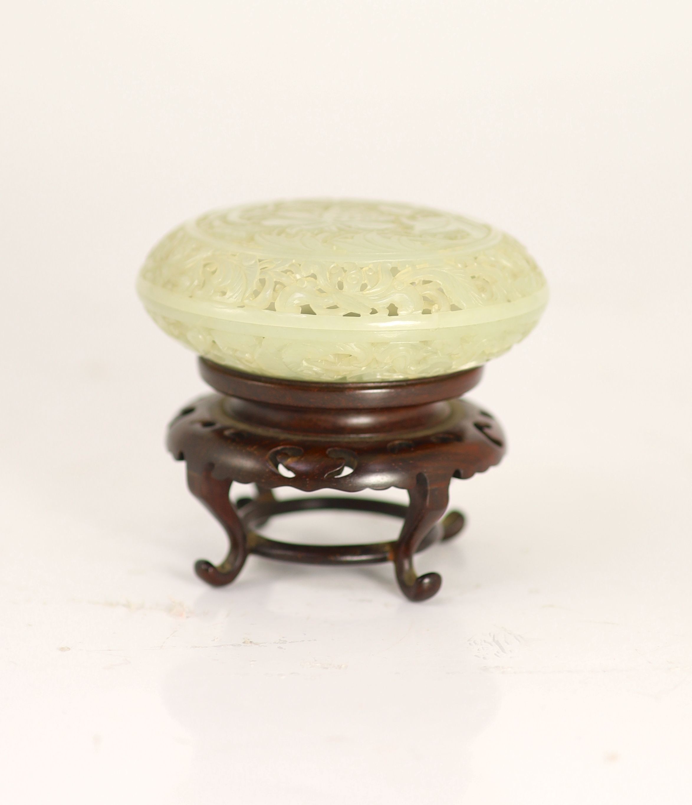 A fine Chinese pale celadon jade reticulated box and cover, 18th century, 9cm diameter, wood stand